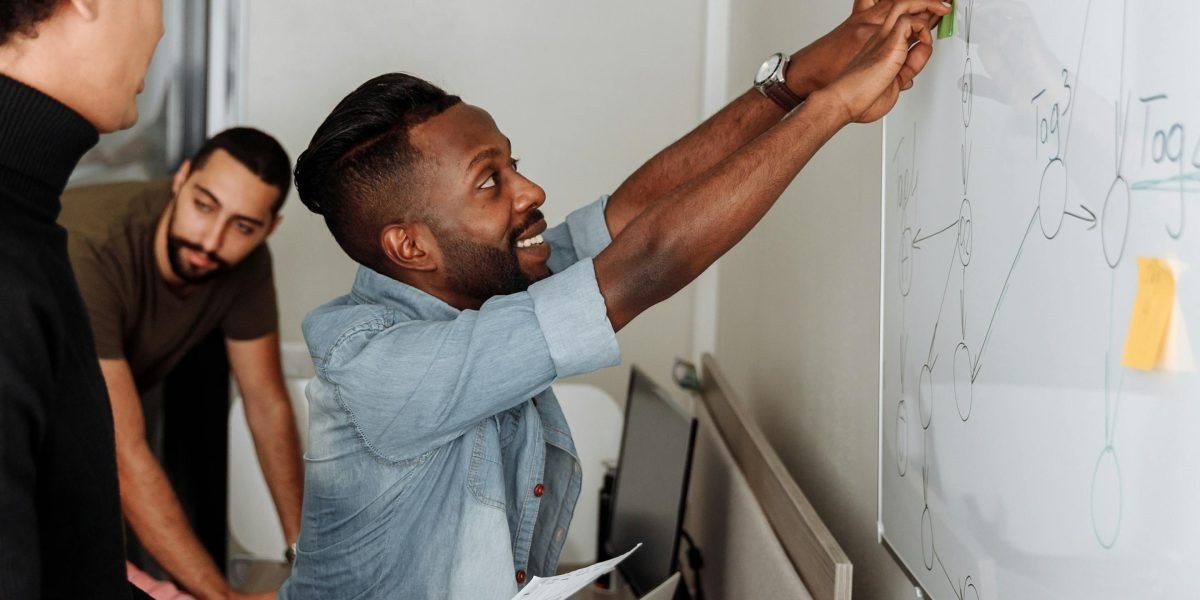 Developers collaborating around a laptop and whiteboard