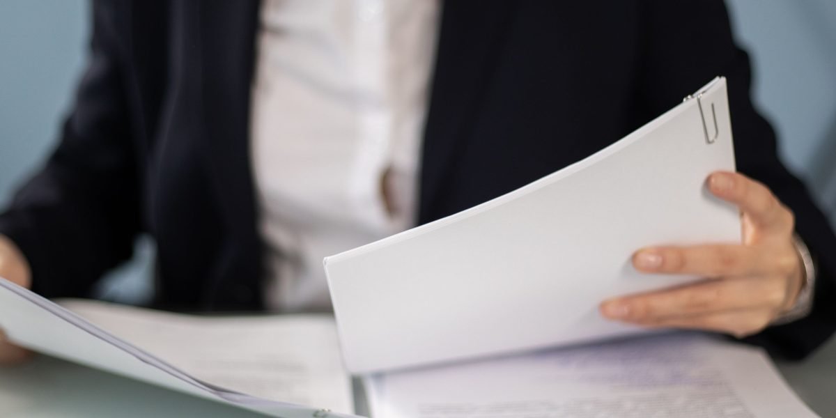 An individual intently reviewing documents, representing the crucial task of monitoring and auditing AI systems for compliance.
