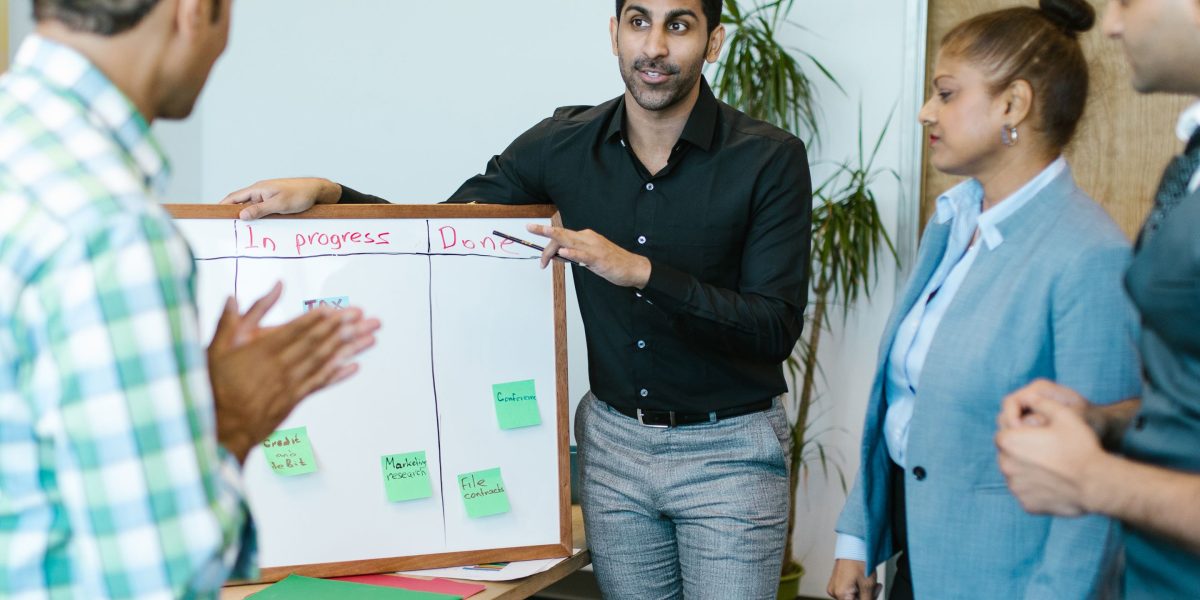 A group of professionals actively brainstorming ideas on a whiteboard, symbolizing collaborative problem-solving and innovation.