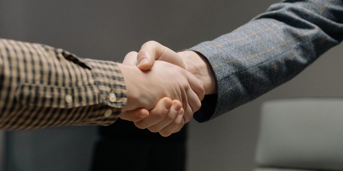 Two professionals shaking hands, signifying a successful job offer or partnership, often influenced by in-demand skills.